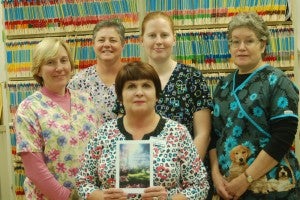 Kelly Brooks, center, holds one of the sympathy cards Ridge Animal Hospital routinely sends to clients whose pets have passed away. Brooks, who initiated the Pet Luminary Service planned for Dec. 5, is pictured with Ridge Animal staff members, from left, standing, Reinette Januszkiewicz, Alison Bryan, Katie Merkle and Deborah Kennedy.