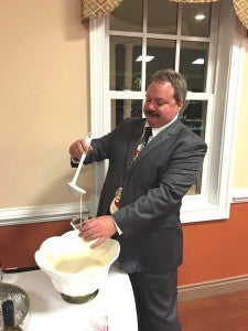 Serving his famous eggnog is Rotarian Kerby Moore.