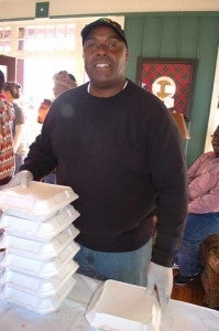 Robert Pew stacks plates as residents line up at the door to receive hot Thanksgiving meals.