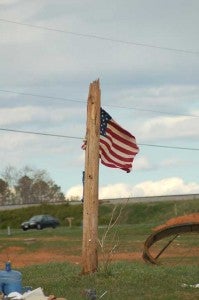 Surrounded by debris, a flag mounted on a broken power pole reflects community pride and determination to carry on.