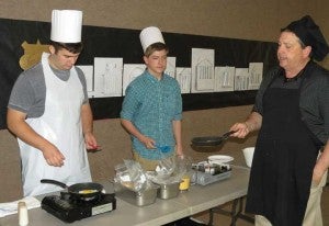 In the Edible Egg workshop, John Ellington, right, director of operations and Fuqua Catering, demonstrates the skill of egg flipping to students Nicholas Davis, left, and Tucker Estes. 