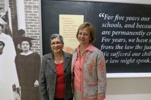 Patsy Franklin, left, and Rockingham County Superintendent Dr. Carol Fenn, pose in the Moton Museum next to the historic photograph of Franklin at the 1965 Free Schools graduation ceremony.