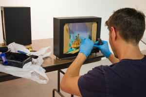 CARSON REEHER | HERALD Elly’s husband, Simon, helps her construct stages and boxes for her art. Prior to the art opening, he could be found arranging hand-made light boxes, which showcase Elly’s small worlds.