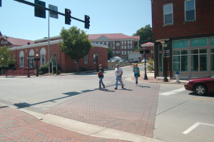 MARTIN L. CAHN | HERALD TOURING — Leanne Sims, left, her father, Edward; and Ukranian exchange student Valeriya Petrechkiv, right, cross Main Street at High Street. Edward Sims said they are hosting Valeriya for the year and were using Labor Day to take her on a tour of Farmville.