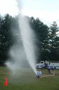 MARTIN L. CAHN Water sprays upward following a successful run in the 6-person hose event by one of the dozen teams competing on Sept. 17 in Farmville.