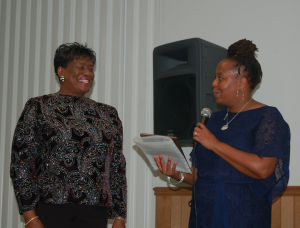 Former educator Shirby Scott-Brown, left, listens as Wendy Lyle-Jones reads from the “Continuing the Legacy” plaque presented to her. 