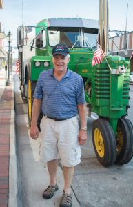 CARSON REEHER | HERALD C. Ivan Stoltzfus stands with his “JohnBilt” tractor while stopped on Main Street to visit friends at Amish Originals.