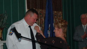 MARTIN L. CAHN | HERALD Tracey Ellington pins her husband’s chief’s badge on his shirt after his swearing-in Thursday at the historic Farmville Train Station.