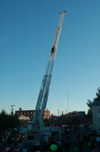 MARTIN L. CAHN | HERALD A firefighter climbs back down a Prince Edward County fire department ladder truck’s ladder reaching high into the Friday afternoon sky from the Farmer’s Market parking lot during New Life Church’s Fall Fest.