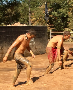 Fuqua School students Isaac Drummond, left, in black shorts, and Andrew Horton, right, in red shorts, compete in the Underwater Wall where you have to jump into the water pit on the other side and then duck or dive under the wall to emerge on the other side.