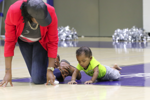 Angelica Tandy tries to coax her son, Joel Saunders, to crawl after taking off his socks to allow him to have more traction.